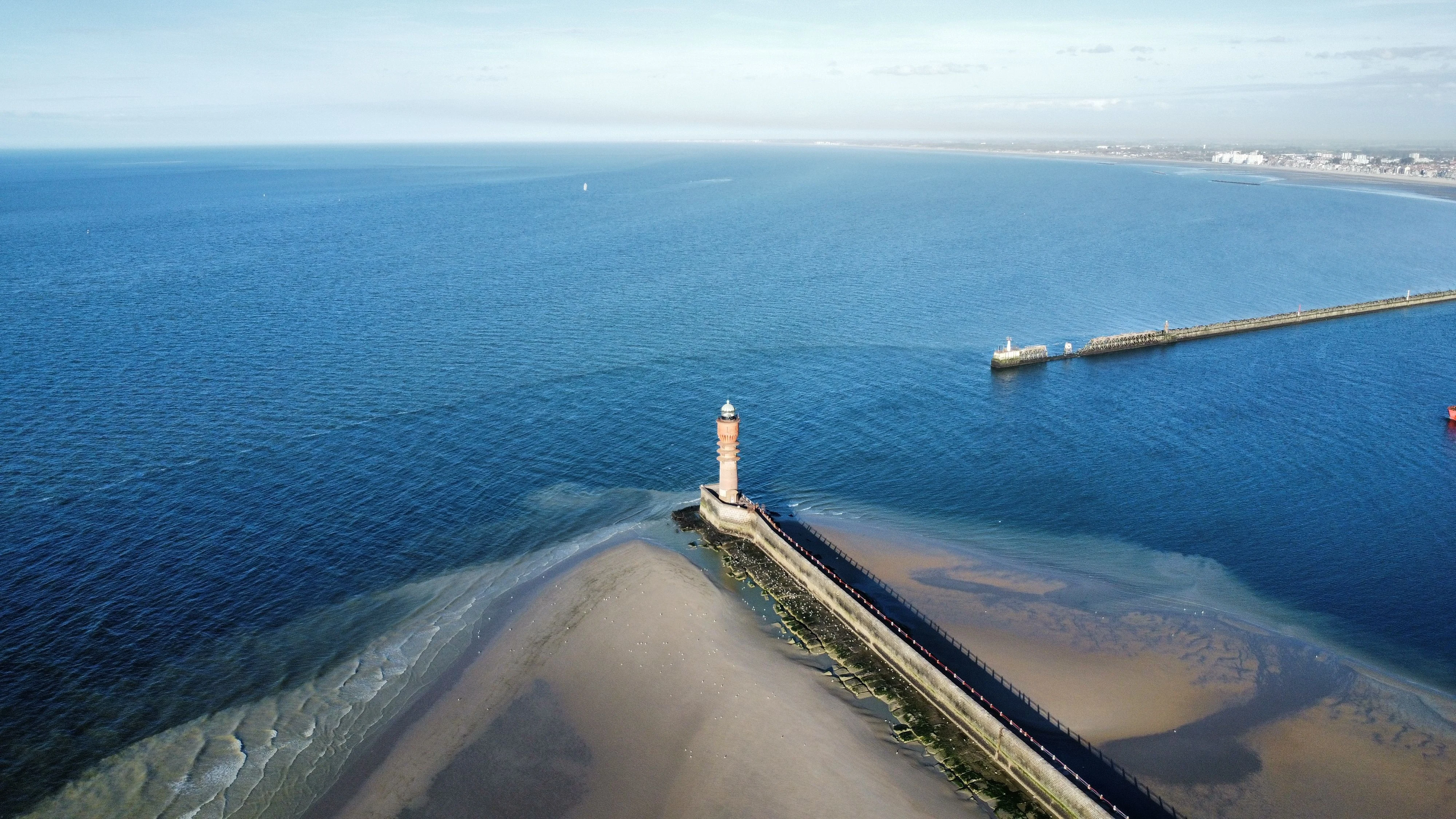 Superbe vue aérienne du phare de Dunkerque sur la côte française, se fondant dans l'immensité bleue de la mer.